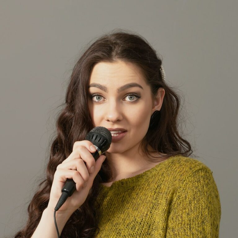 attractive teenager woman speaking with a microphone against gray background, speech presentation