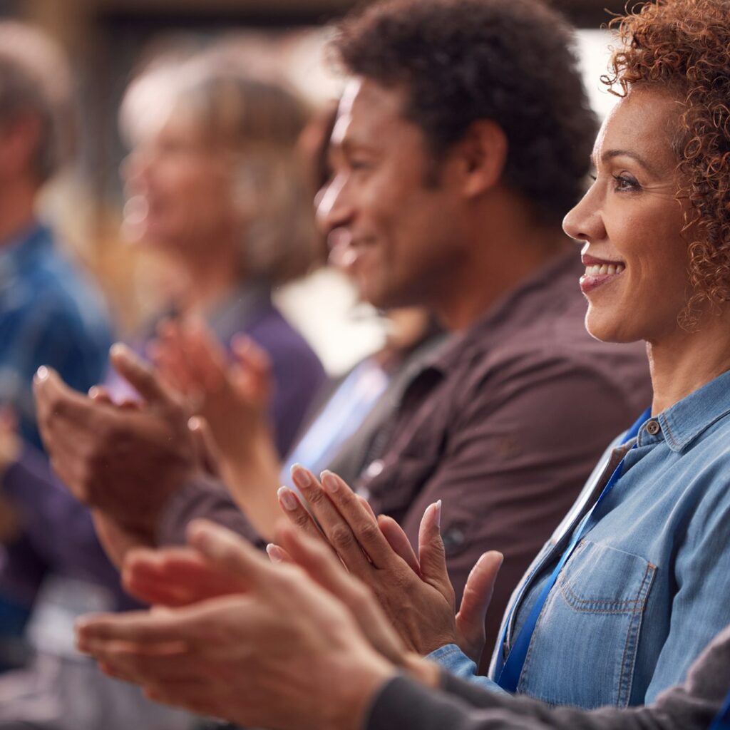 Group Of Casually Dressed Businessmen And Businesswomen Applauding Presentation At Conference