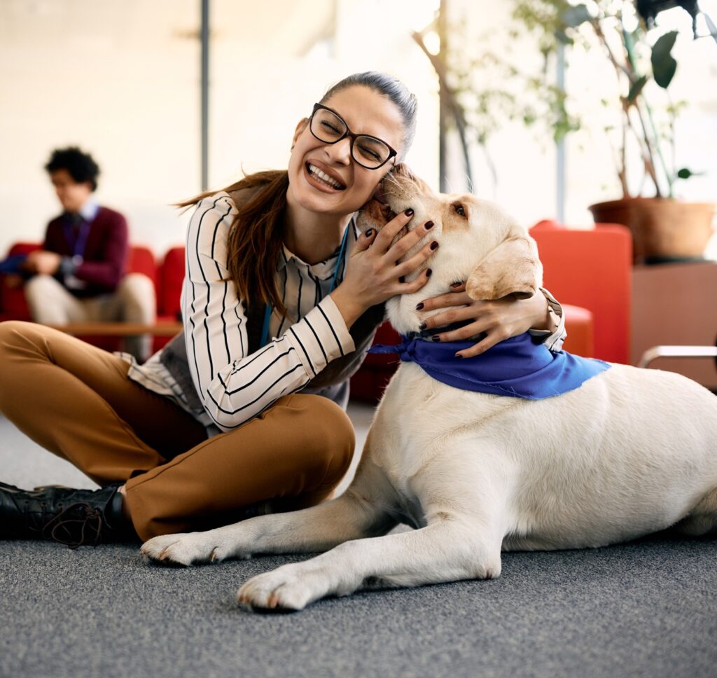Happy businesswoman enjoying with therapy dog in the office.